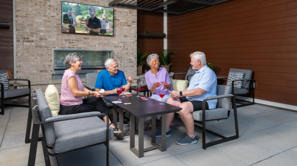 Mature friends laugh and smile over cards in the outdoor area of black hill