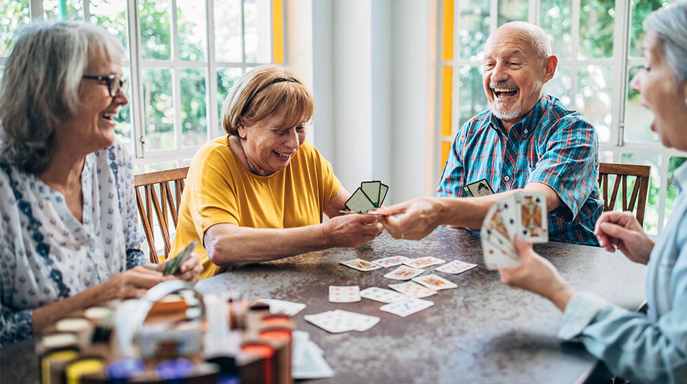 Mature friends laugh and smile over card game