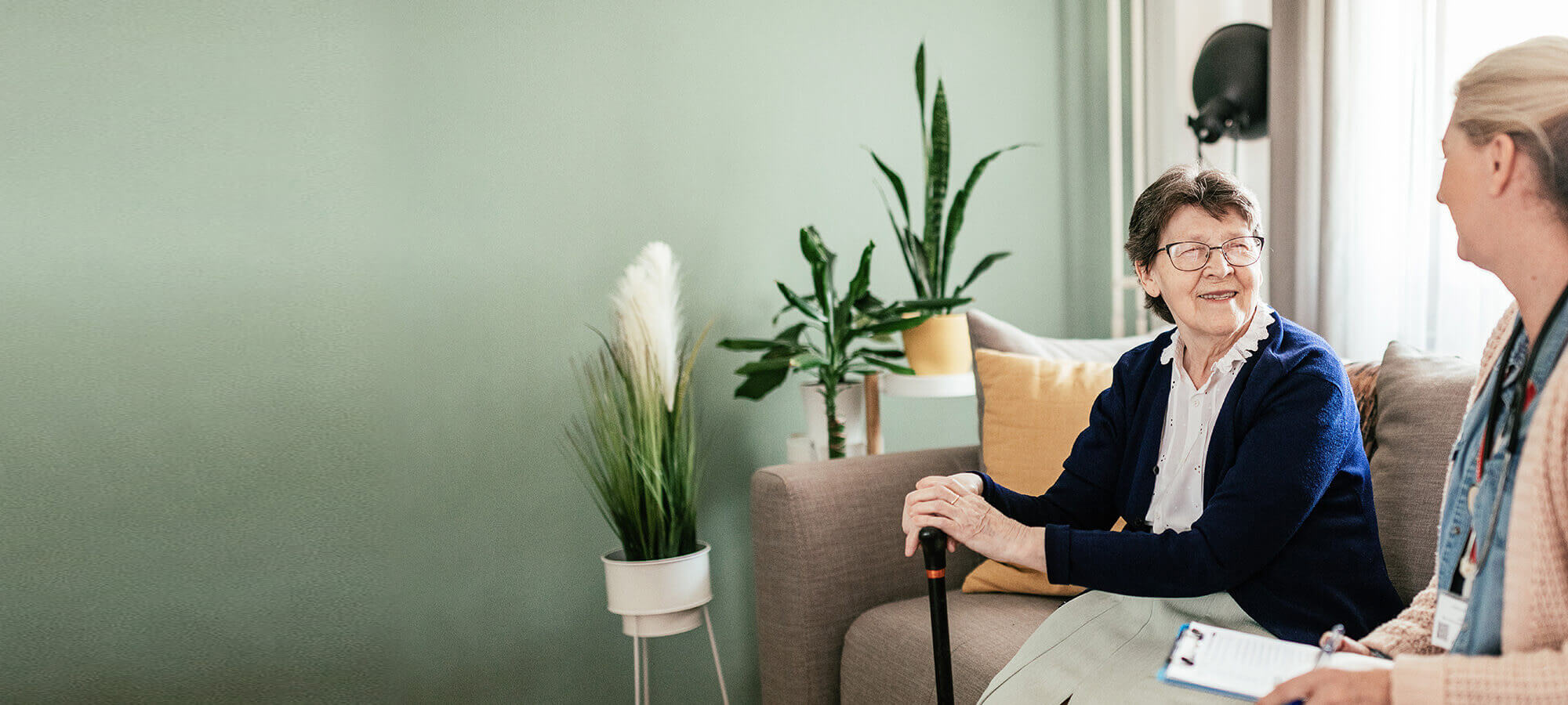 Smiling senior living resident consults with physician on warmly lit couch