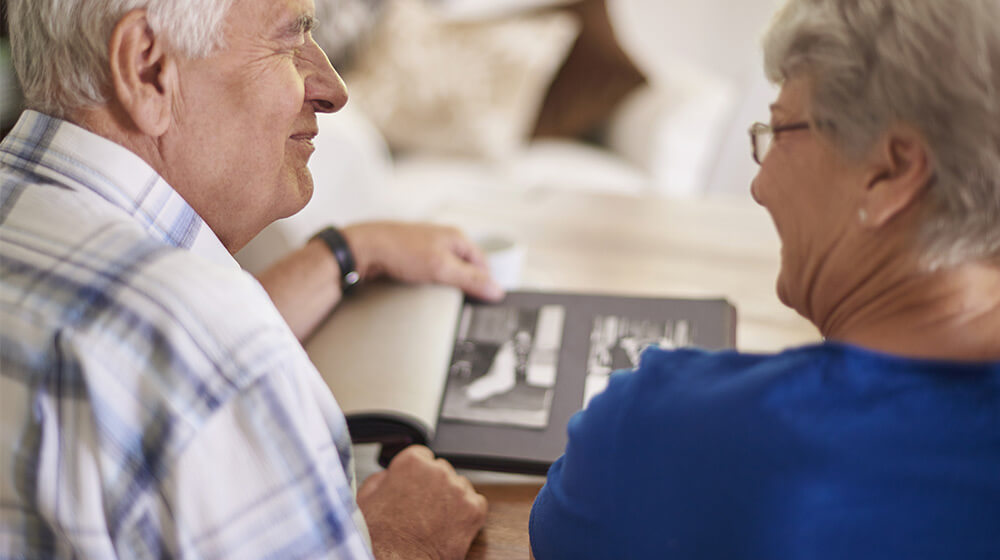 Elderly couple look through wedding photo album together