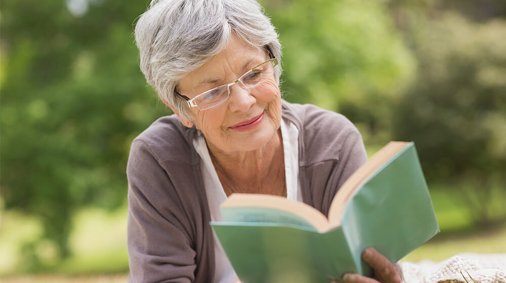 Mature women and friend share the experience of reading outdoors