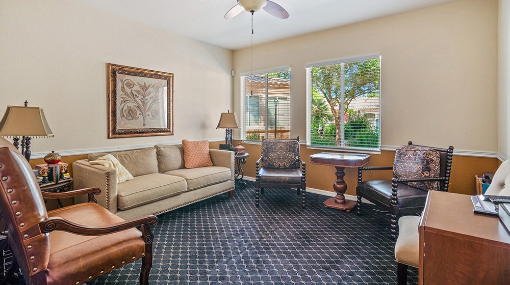 Room with a couch and several armchairs arranged in front of a wall-mounted tv at The Montecito Senior Living